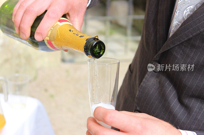 新郎在婚礼上倒香槟，香槟酒杯/酒杯，起泡酒